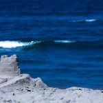 A single round sand castle with blue ocean in the background