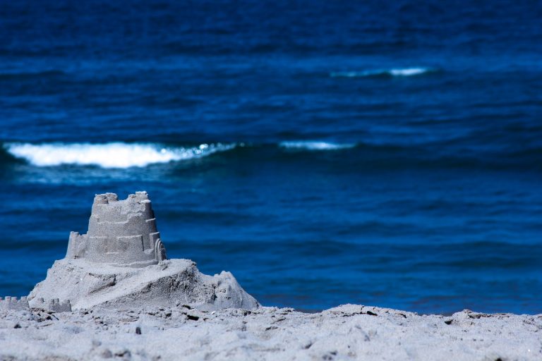 A single round sand castle with blue ocean in the background